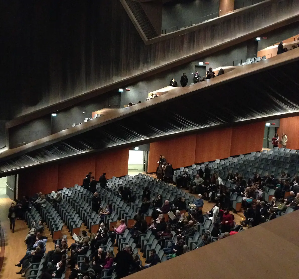 Rows of grey seats and dark balconies inside a modern opera house auditorium in Florence