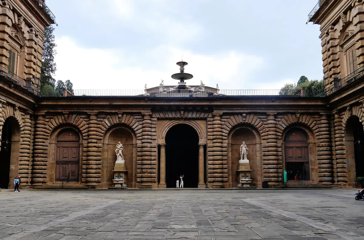 The tall rusticated courtyard of Palazzo Pitti in Florence, with a fountain at the far end under a wide arch